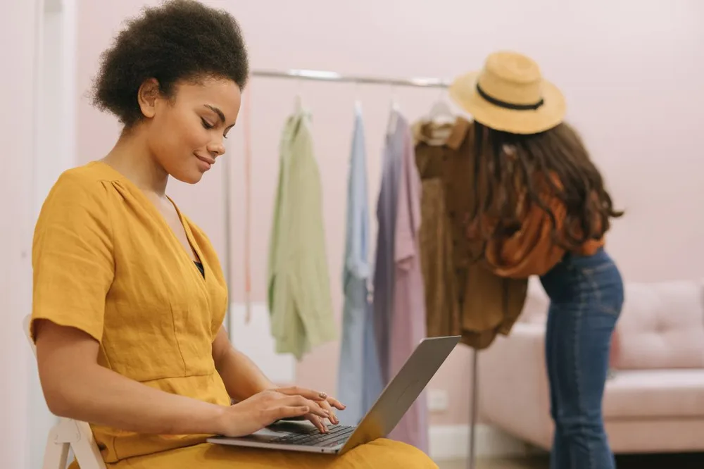 Woman working on a laptop in a small clothing shop